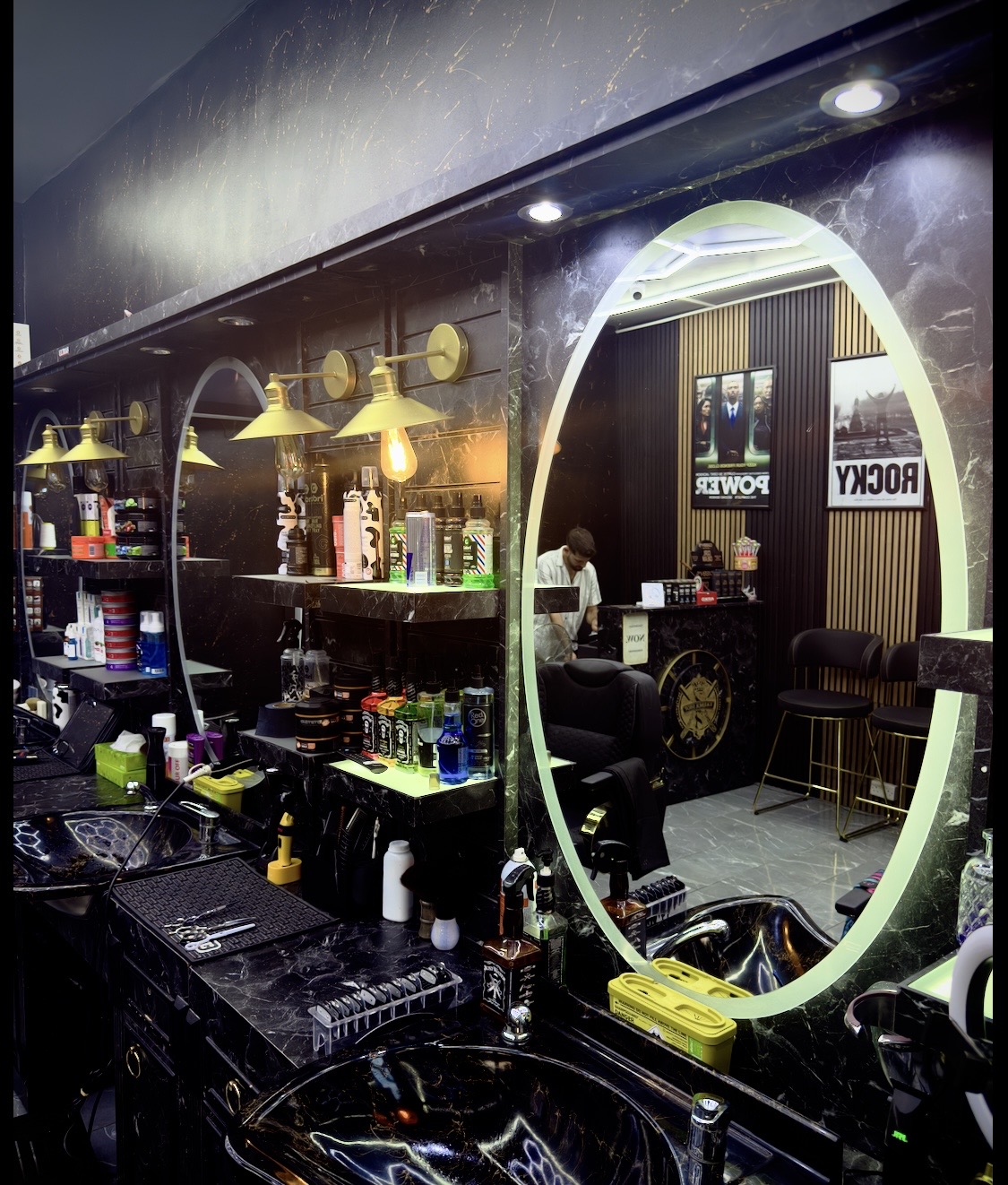 Xalo Barbers interior with black marble stations, gold lamps, and lit round mirrors